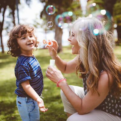 Mom and child blowing bubbles together in the park