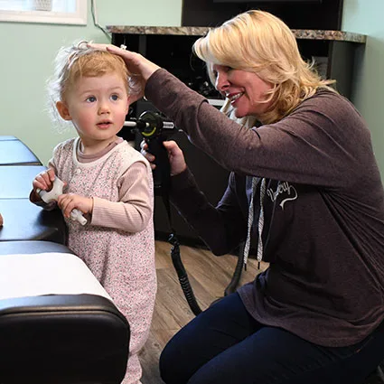 Dr. Saylor gently checking a young child's neck